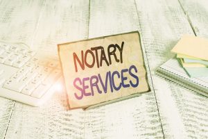 A notary services sign shown with keyboard and paper setting on a wooden table