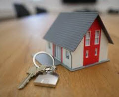 Small toy house and a key on a key ring displayed on a table